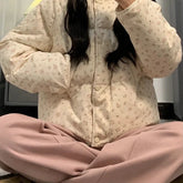 Person wearing a floral patterned puffer jacket and pink pants indoors.